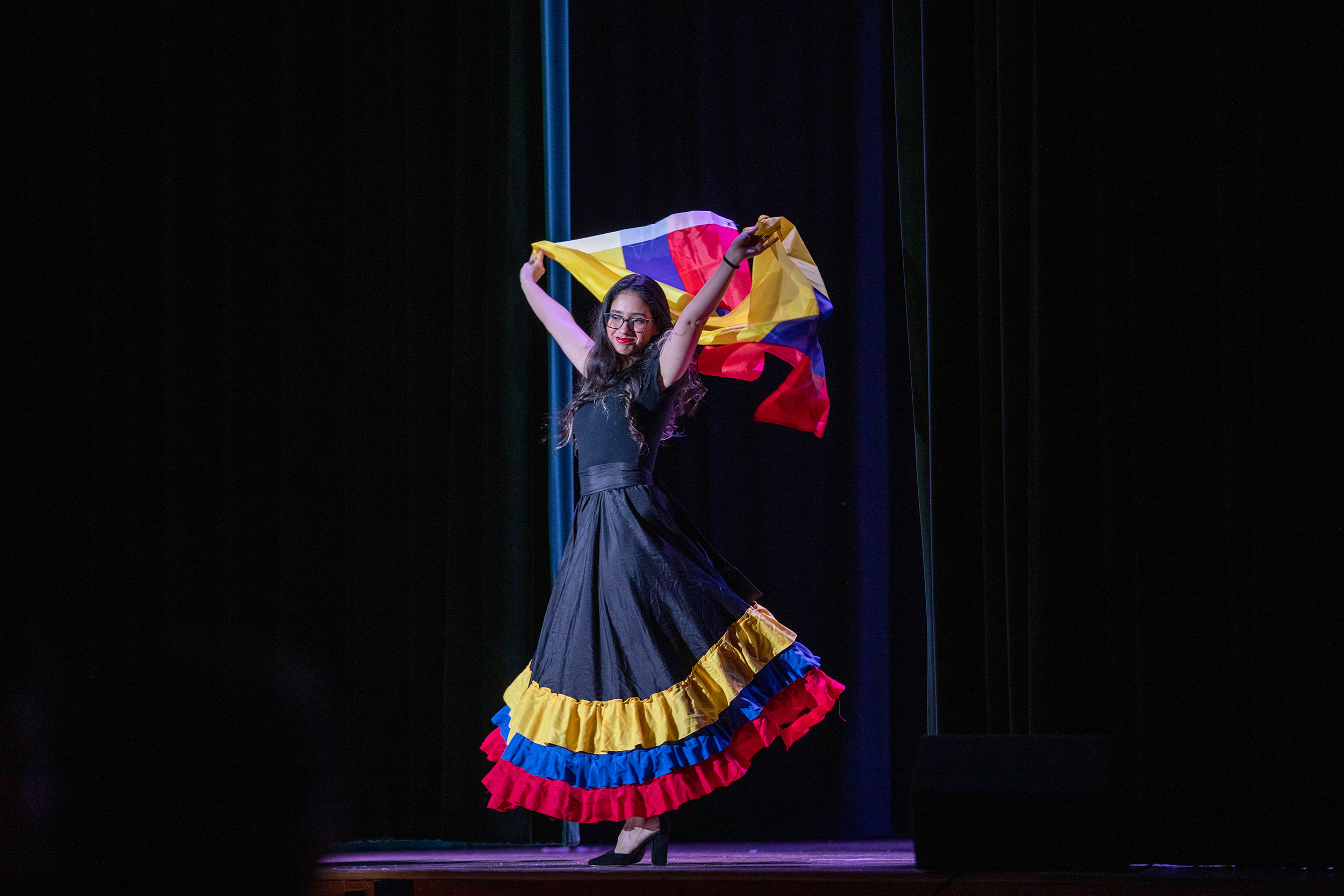 A student performing for Latin American Club Night wears a traditional folkloric dress that bears the colors of the Colombian flag.