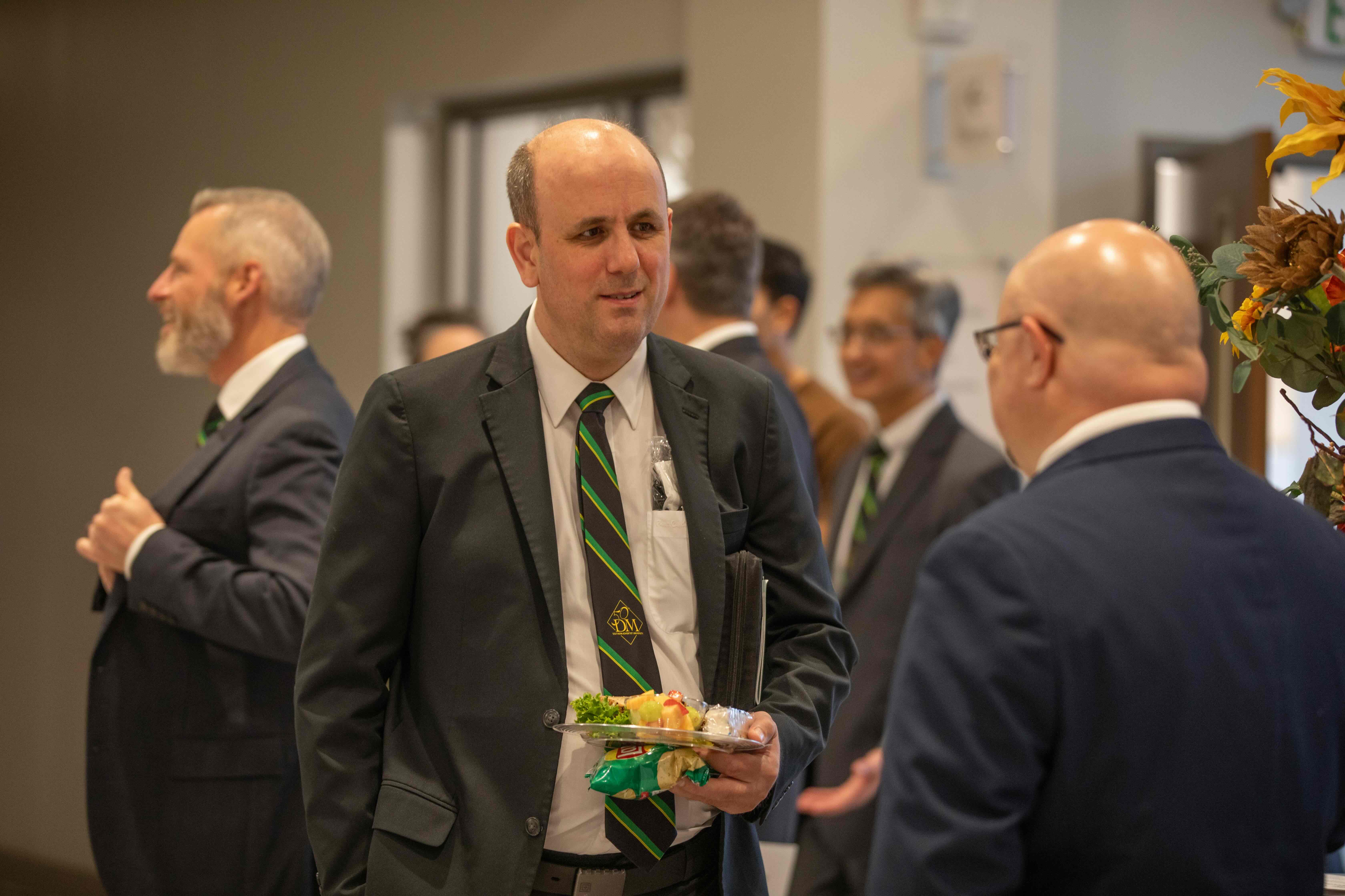 an alumni wearing a Die Meistersinger 50th reunion tie talking with another singer