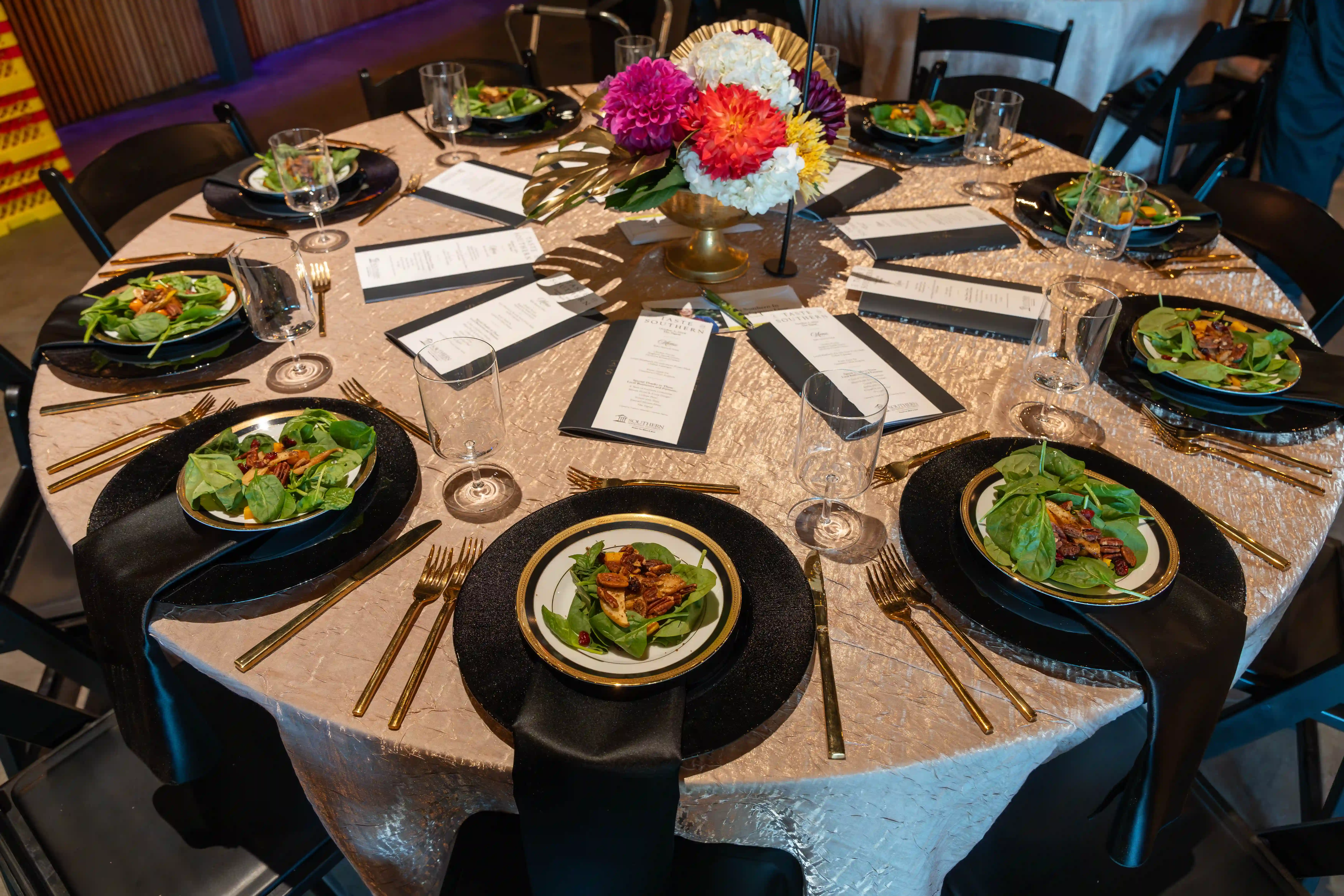 A table set beautifully with black plates and salad