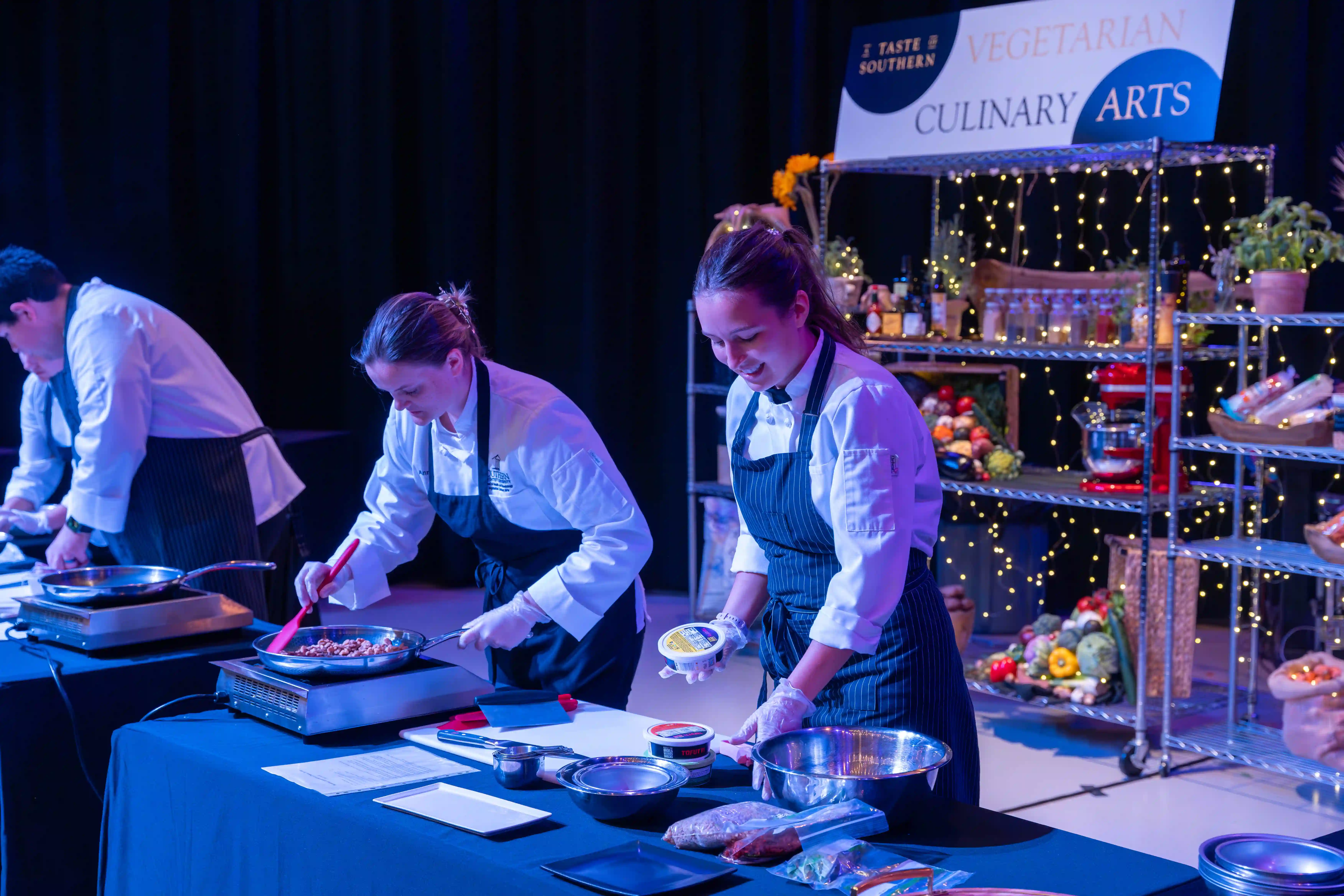 Culinary art students and faculty demonstrating cooking techniques at a table