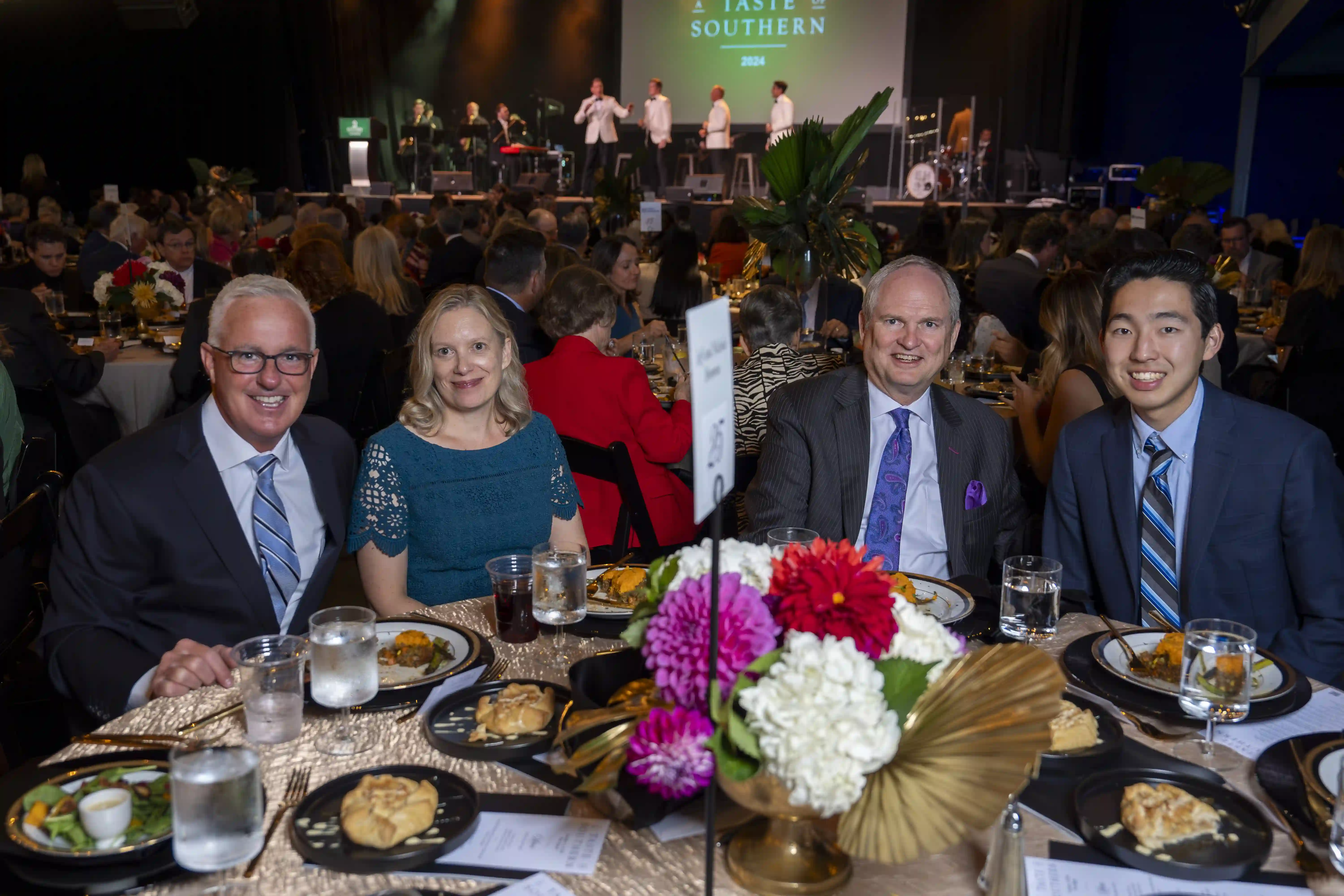 Scott Falk, Kirstin Falk, Jeff Bromme, and Nathan Turner sitting at a table, posing for the photo