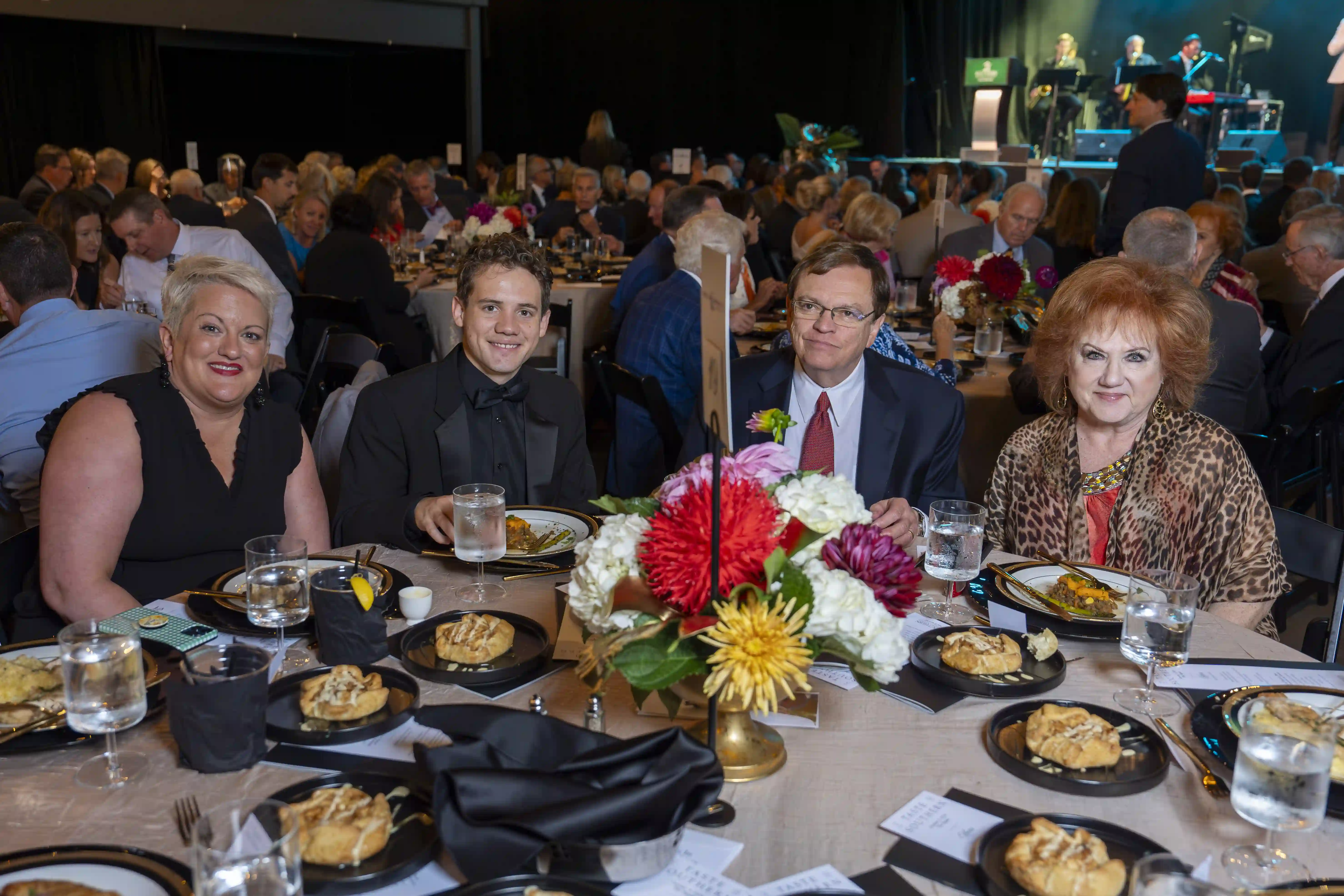 Susan Gee, Tommy Ziesmer, Mike Barto, Jane Barto sitting at a table, posing for the photo. 