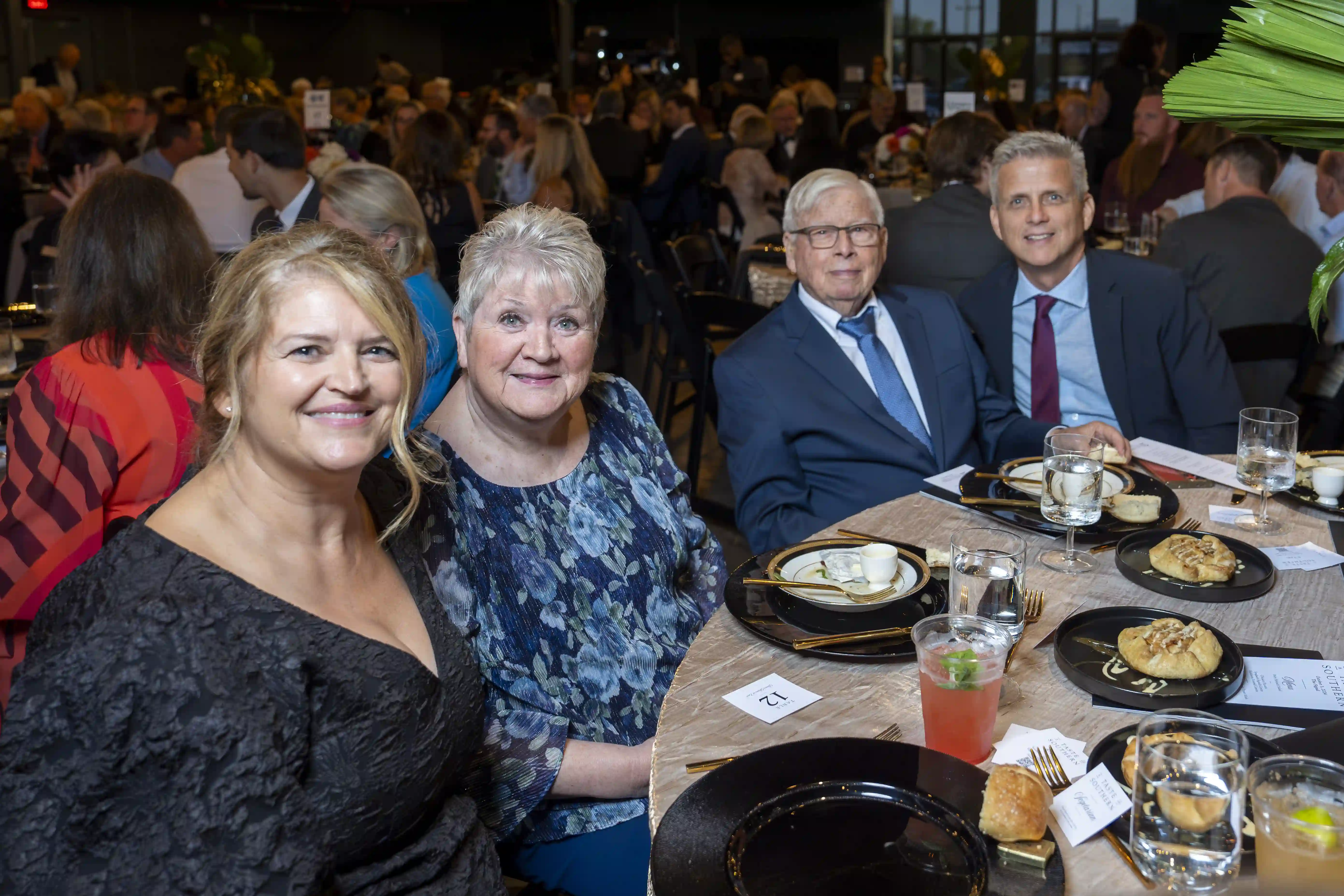 Tanya Jansen, Sonja Johnson, John Shaw, Keith Shaw sit at a round table posing for the picture during the dinner portion of the evening. 