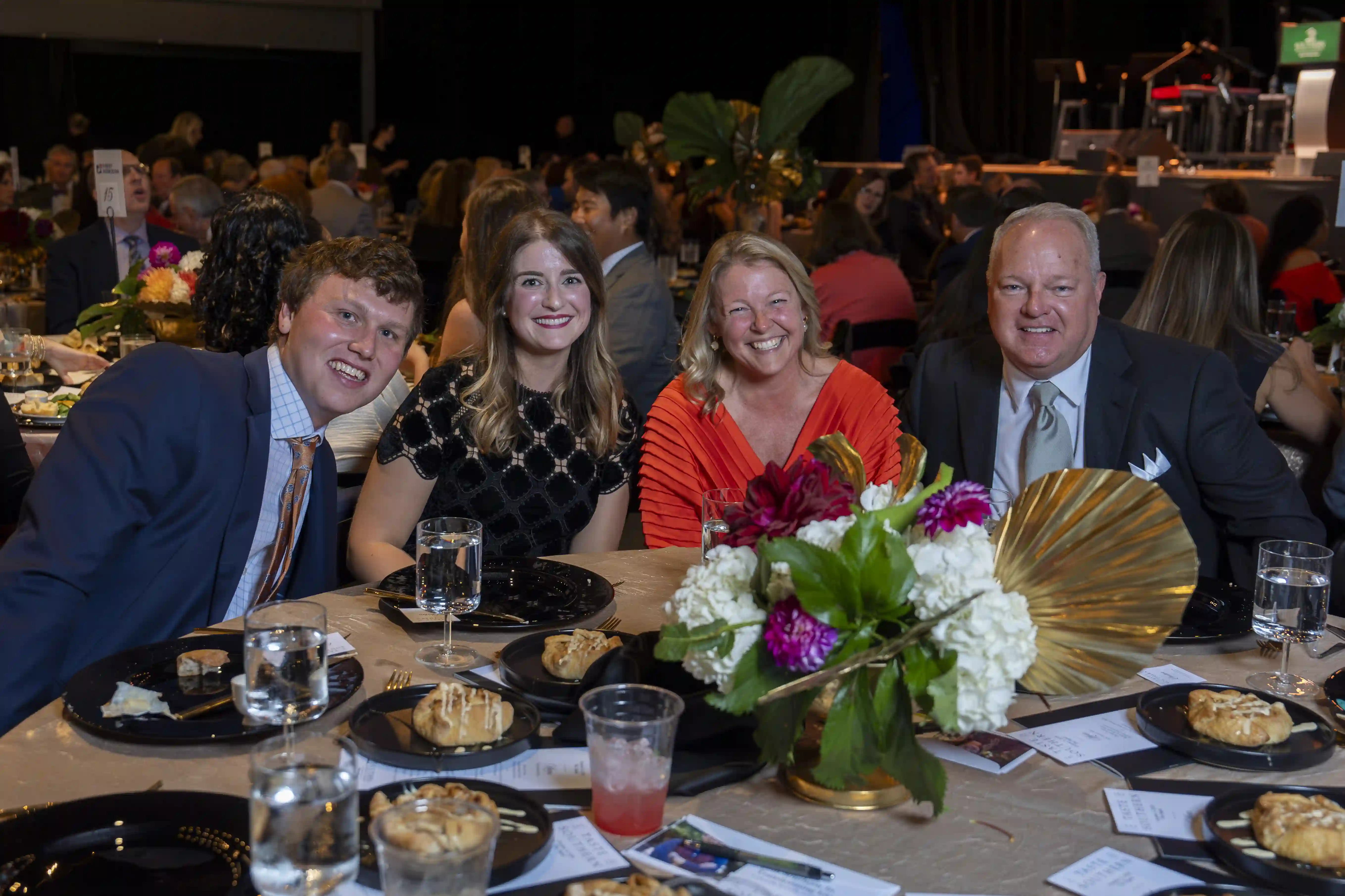 Tucker Sutton, Abby Sutton, Teri Henderson, Joel Henderson sit at a round table posing for the picture during the dinner portion of the evening.