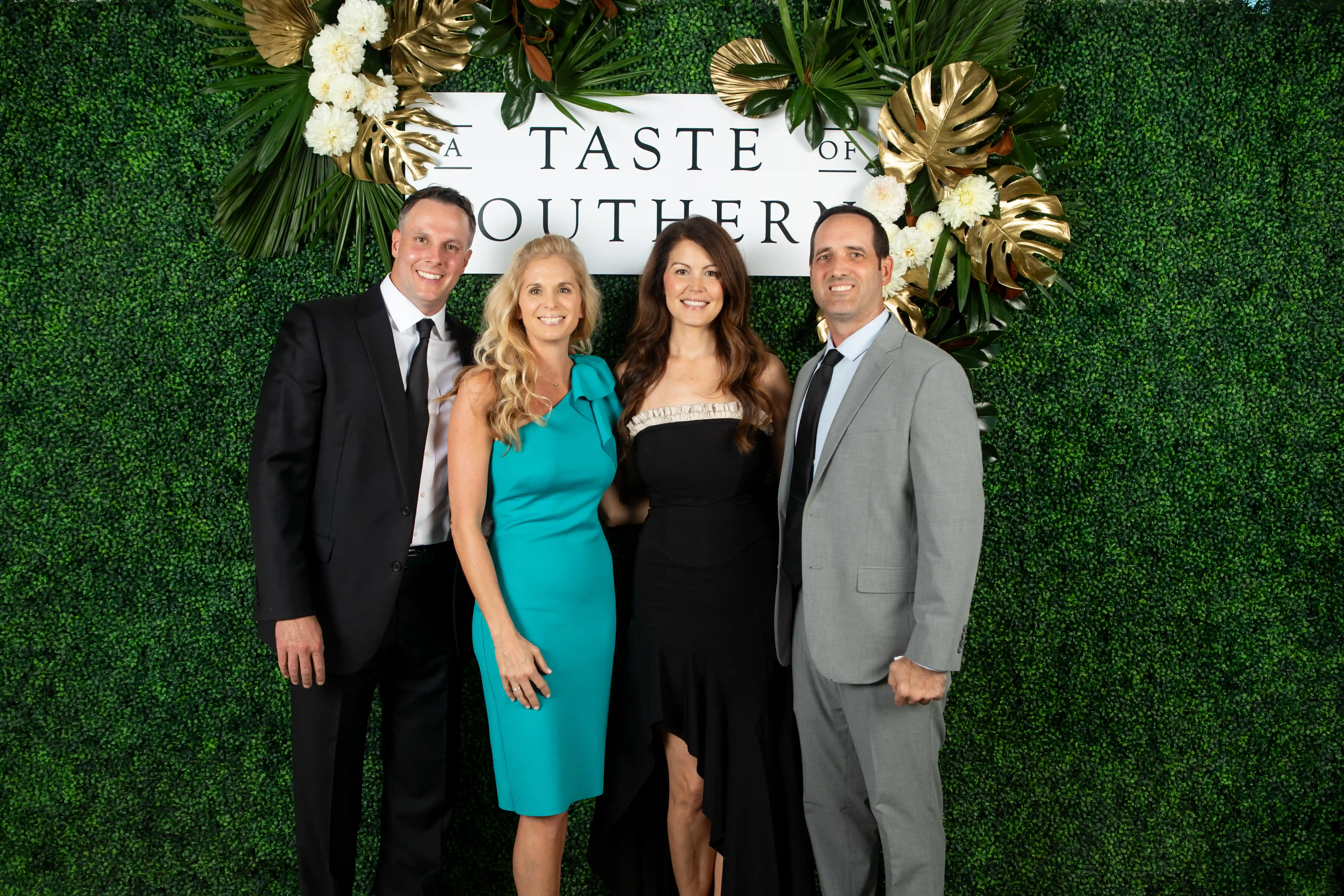 Kris and Kristie Eckenroth standing next to Emily and Eric Dunkel in front of a green backdrop