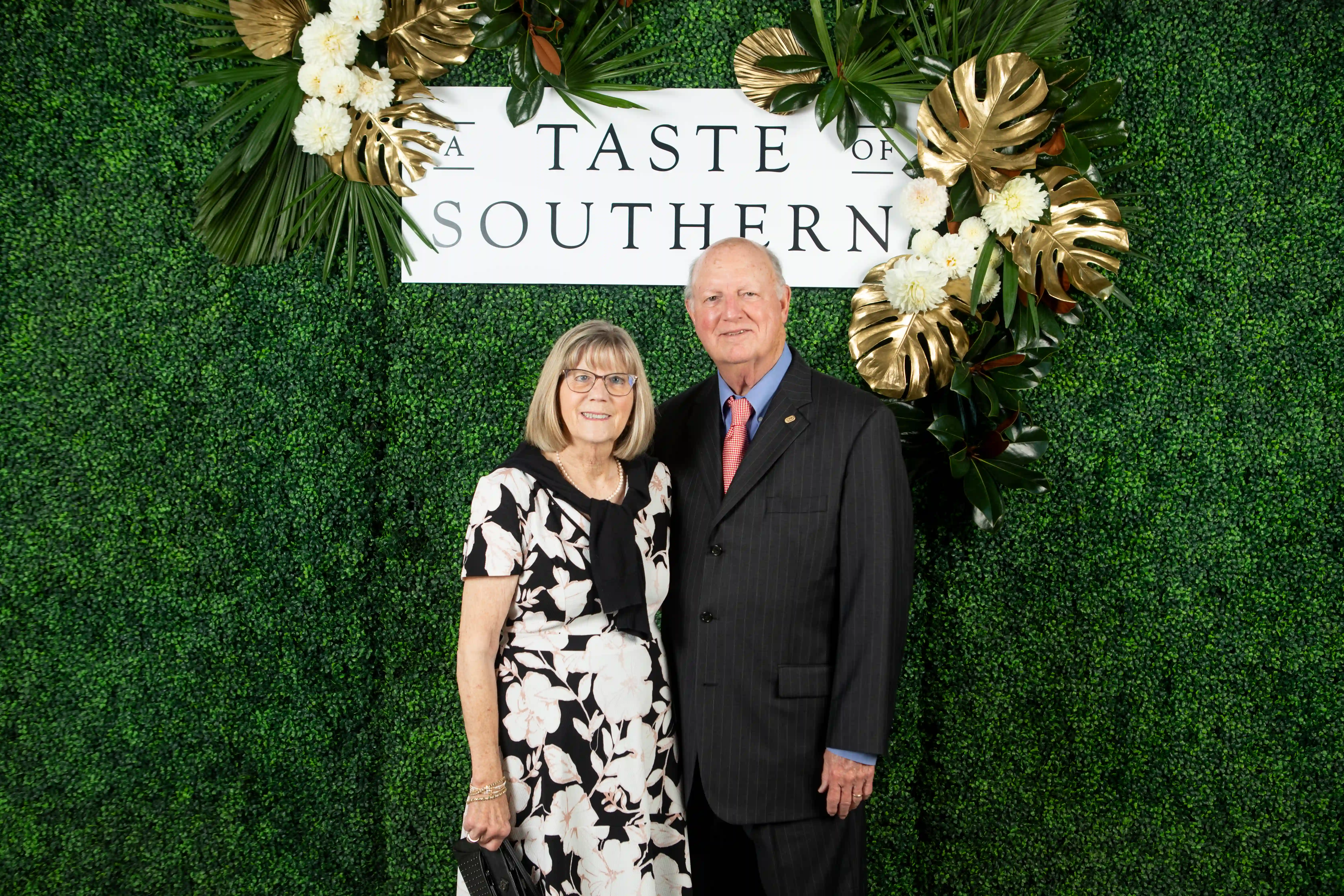 Patsy and Henry Hoss embracing side-by-side in front of a green backdrop