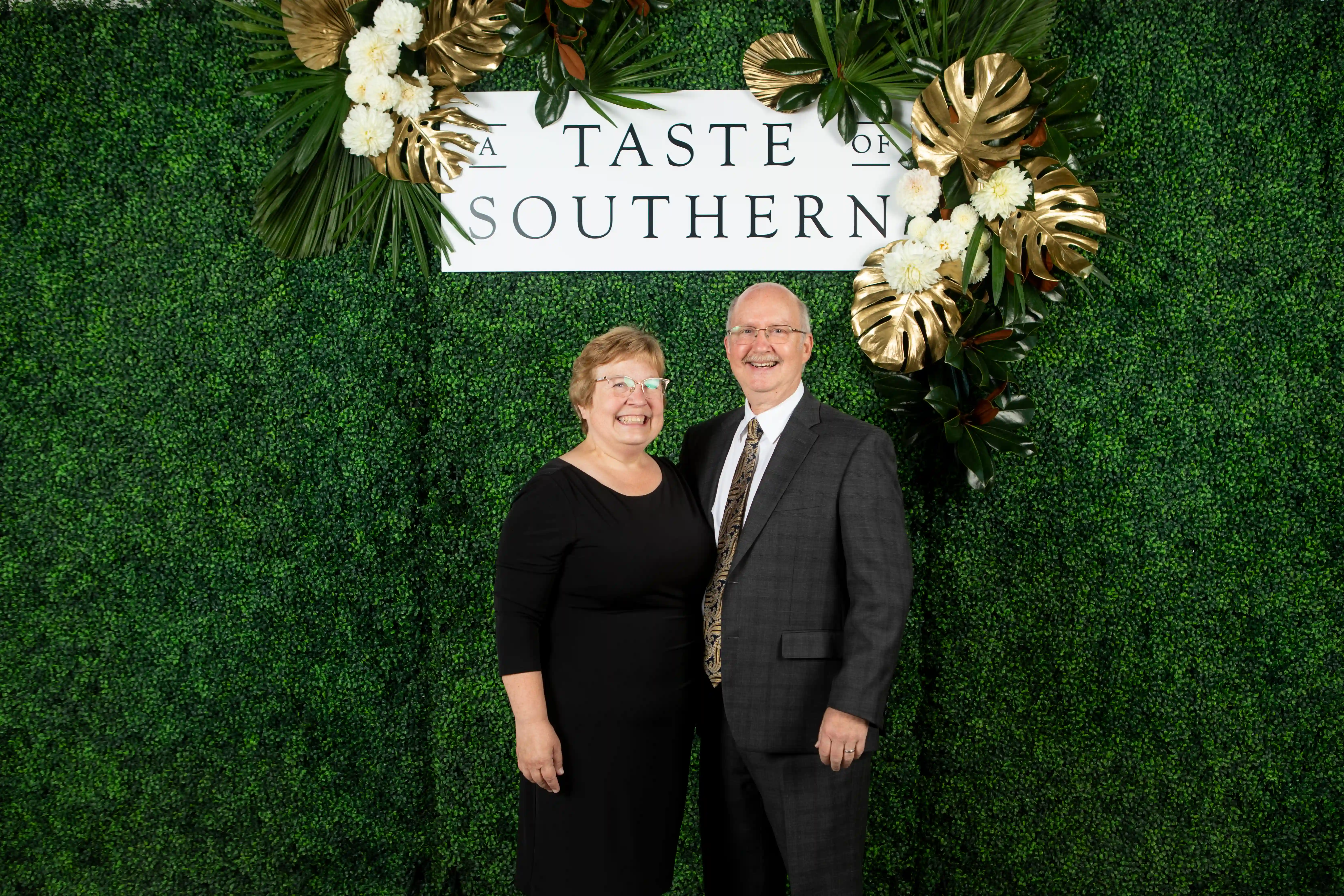 Steven and Sonia Wrate embracing side-by-side in front of a green backdrop