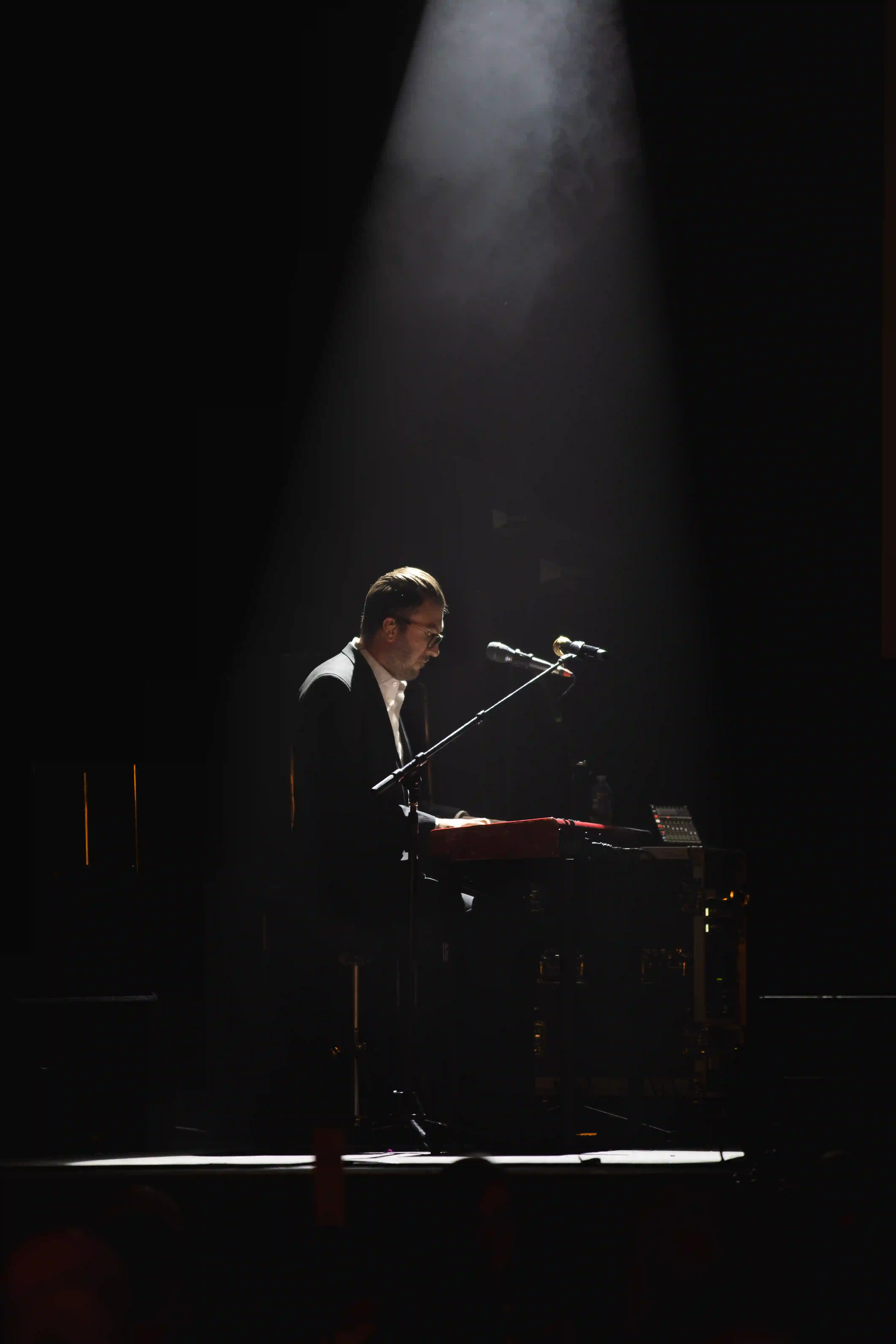 Pianist performs on the stage below a single spotlight overhead