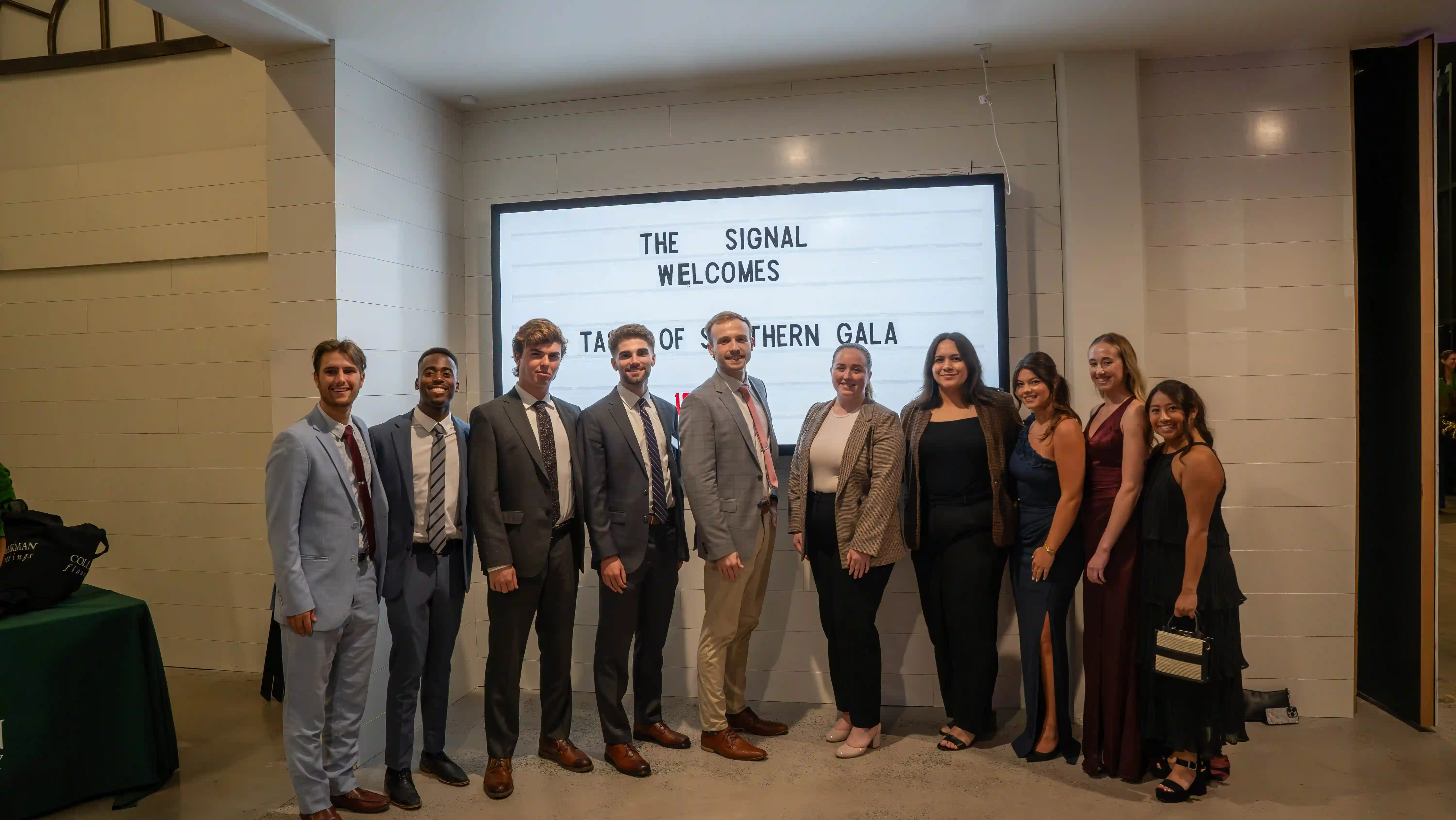 Student interns standing together in front of The Signal digital sign