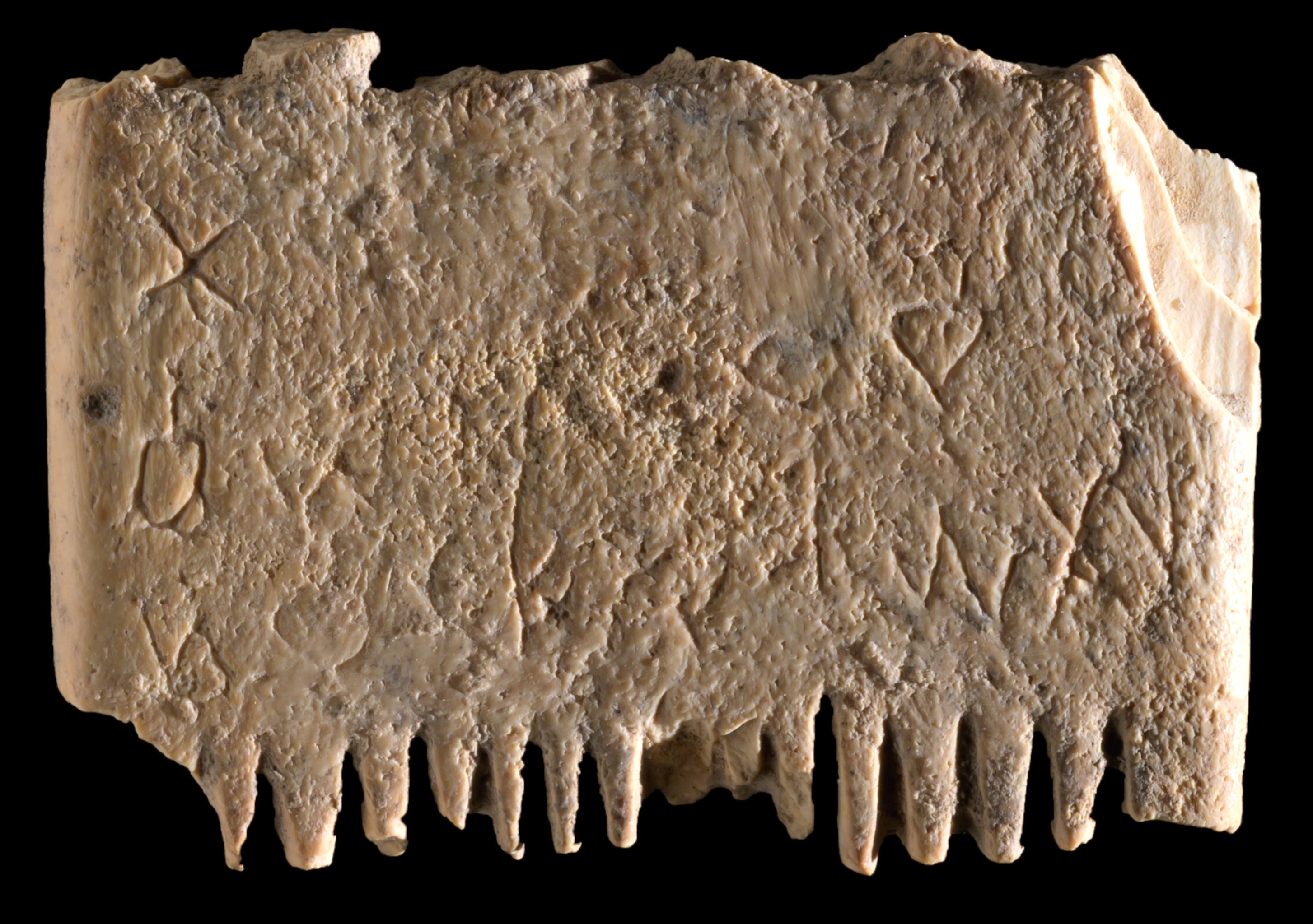 Ivory comb with inscription on a black background.