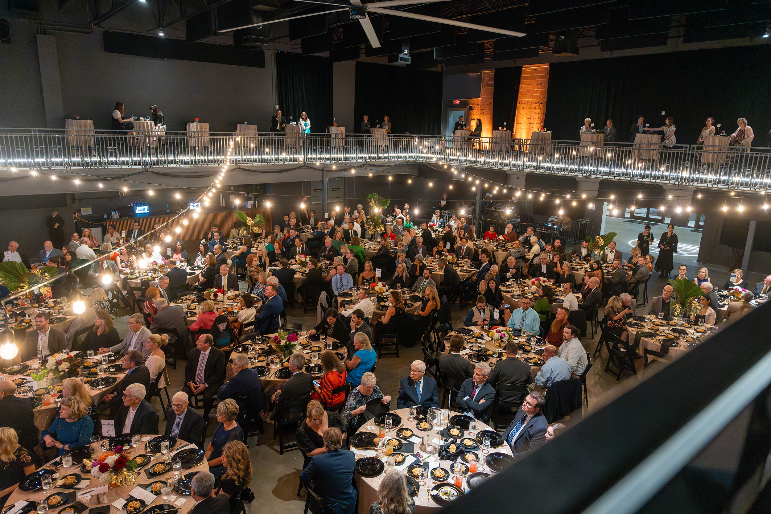 A room full of guests with elegant lighting and tablesettings