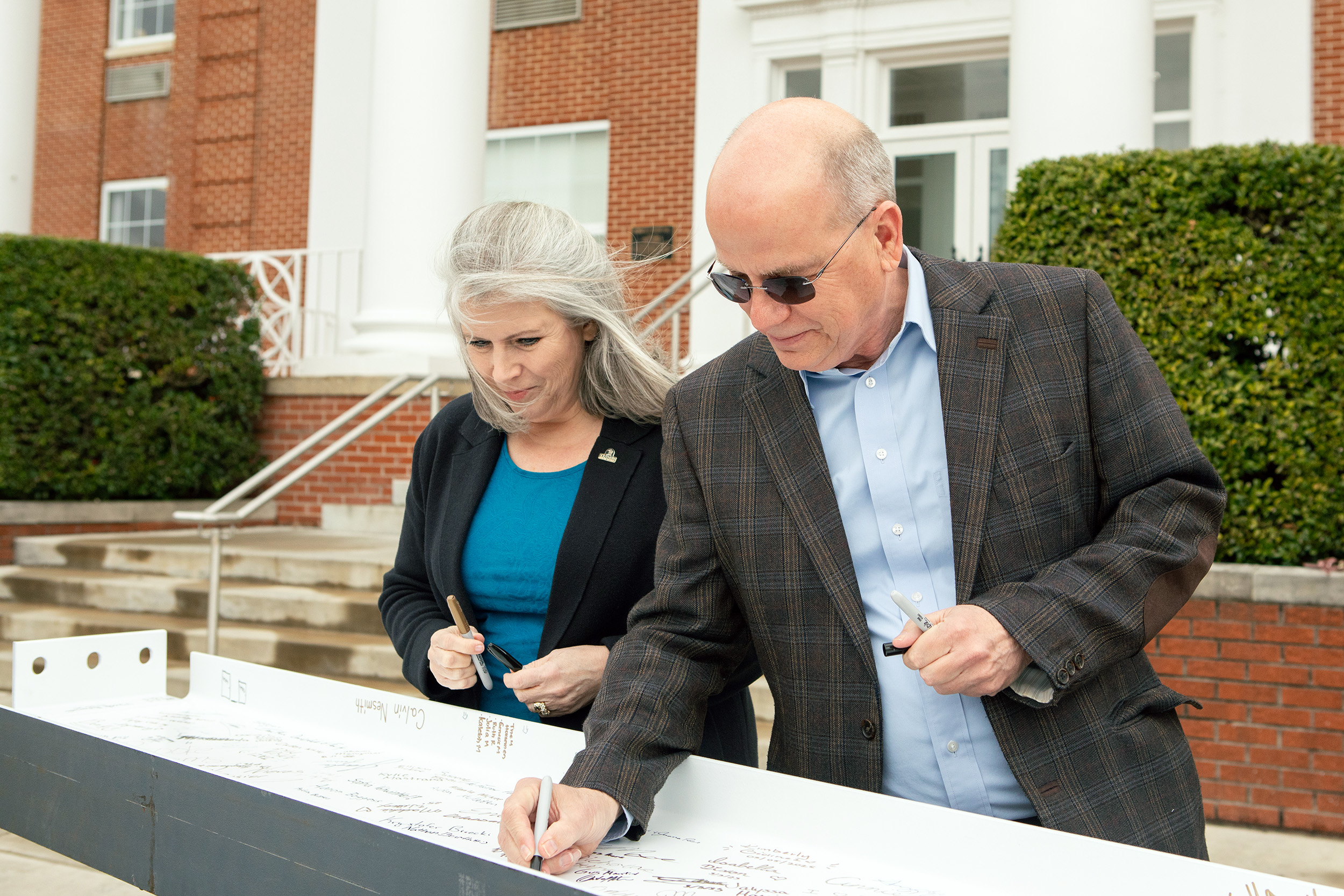 Ken Shaw, president, and Stephanie Sheehan, dean of the School of Business, sign the beam.