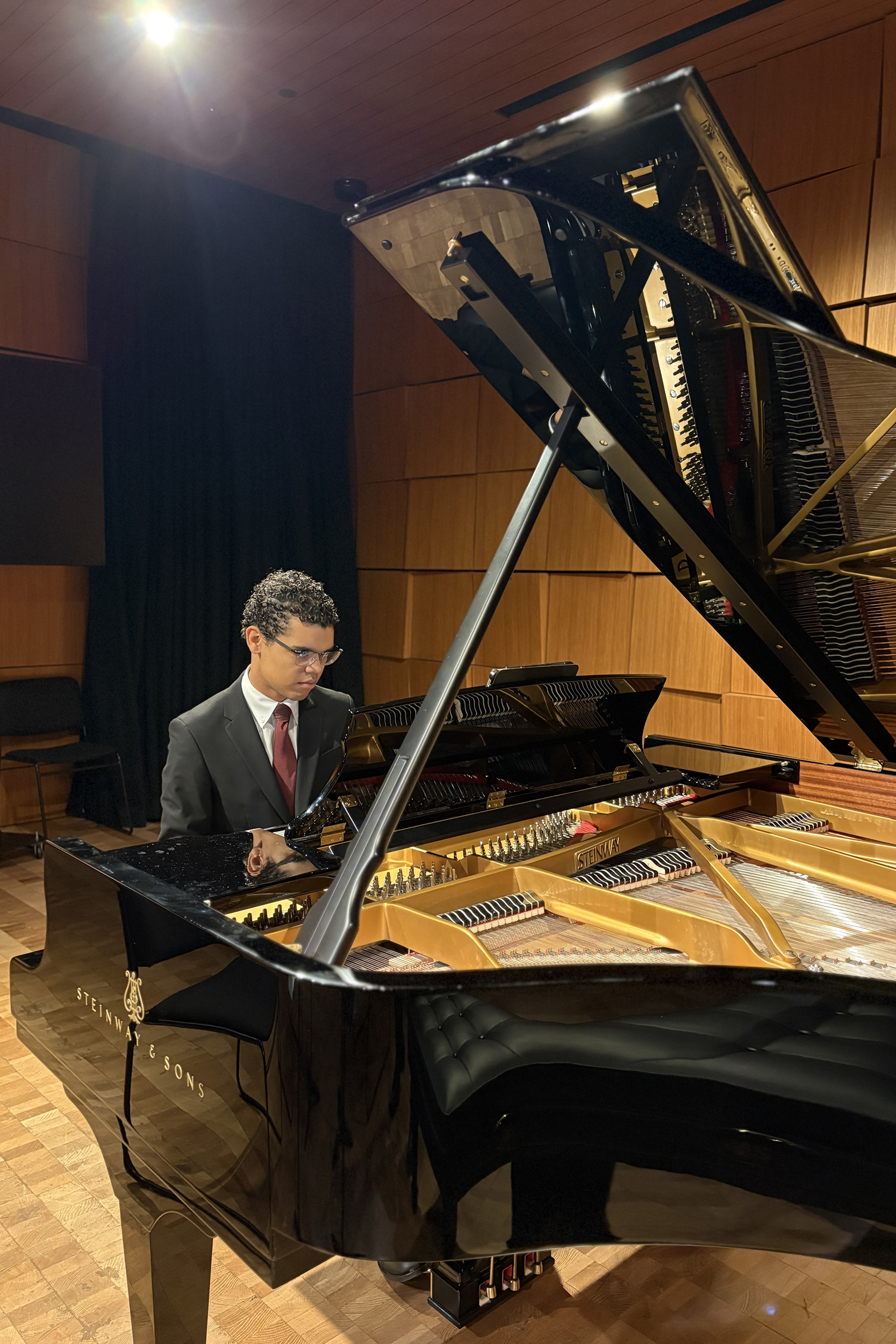 Matthew Kimbley, ’25, practices on a piano in Steinway Hall before performing at the alumni concert.